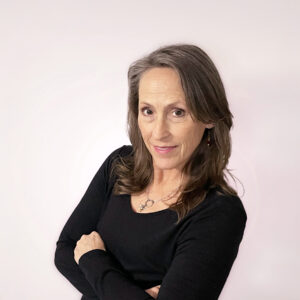 Headshot of Jessie wearing black and a honey bee necklace, with a confident smile.